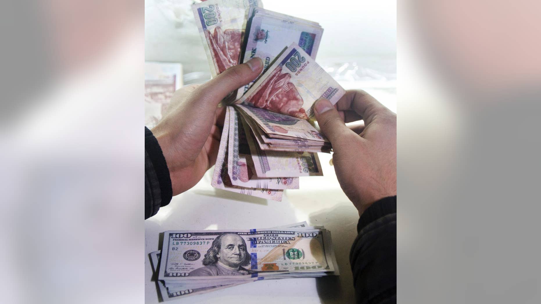 FILE -- In this March 14, 2016 file photo, a man counts Egyptian currency at an exchange office in Cairo, Egypt. On Thursday, Nov. 3, 2016, Egypt devalued its currency by nearly 50 percent, meeting a key demand set by the International Monetary Fund in exchange for a $13 billion loan over three years to overhaul the country’s ailing economy. Thursday’s much heralded decision by the Egyptian Central Bank to devalue the pound followed a sharp and sudden decline this week in the value of the dollar in the unofficial market, plunging from an all-time high of 18.25 pounds to around 13 to the U.S. currency. (AP Photo/Amr Nabil, File)