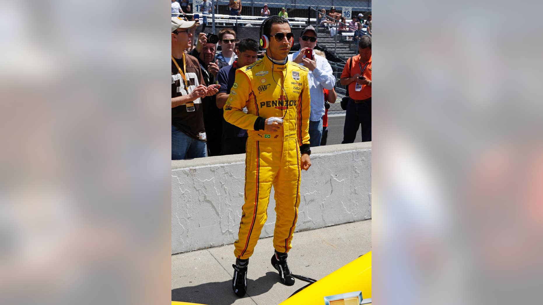 Helio Castroneves, of Brazil, listens to music as he waits for his turn to qualify for the Indianapolis 500 IndyCar auto race at the Indianapolis Motor Speedway in Indianapolis, Sunday, May 18, 2014. (AP Photo/Tom Strattman)