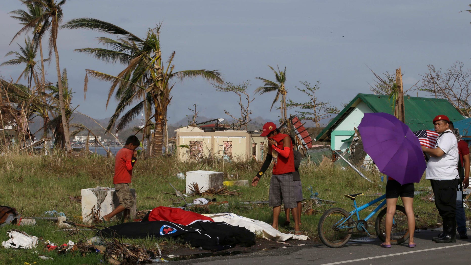 Relatives of Rolando Palermo check cadaver bags containing the remains of typhoon victims along a road in Tacloban city, hoping to find his body Friday Nov. 22, 2013, two weeks after the typhoon struck in central Philippines. Typhoon Haiyan, one of the most powerful typhoons to make a landfall this year, battered central Philippines Nov. 8, leaving a wide swath of destruction. The relatives failed to locate his remains.(AP Photo/Bullit Marquez)