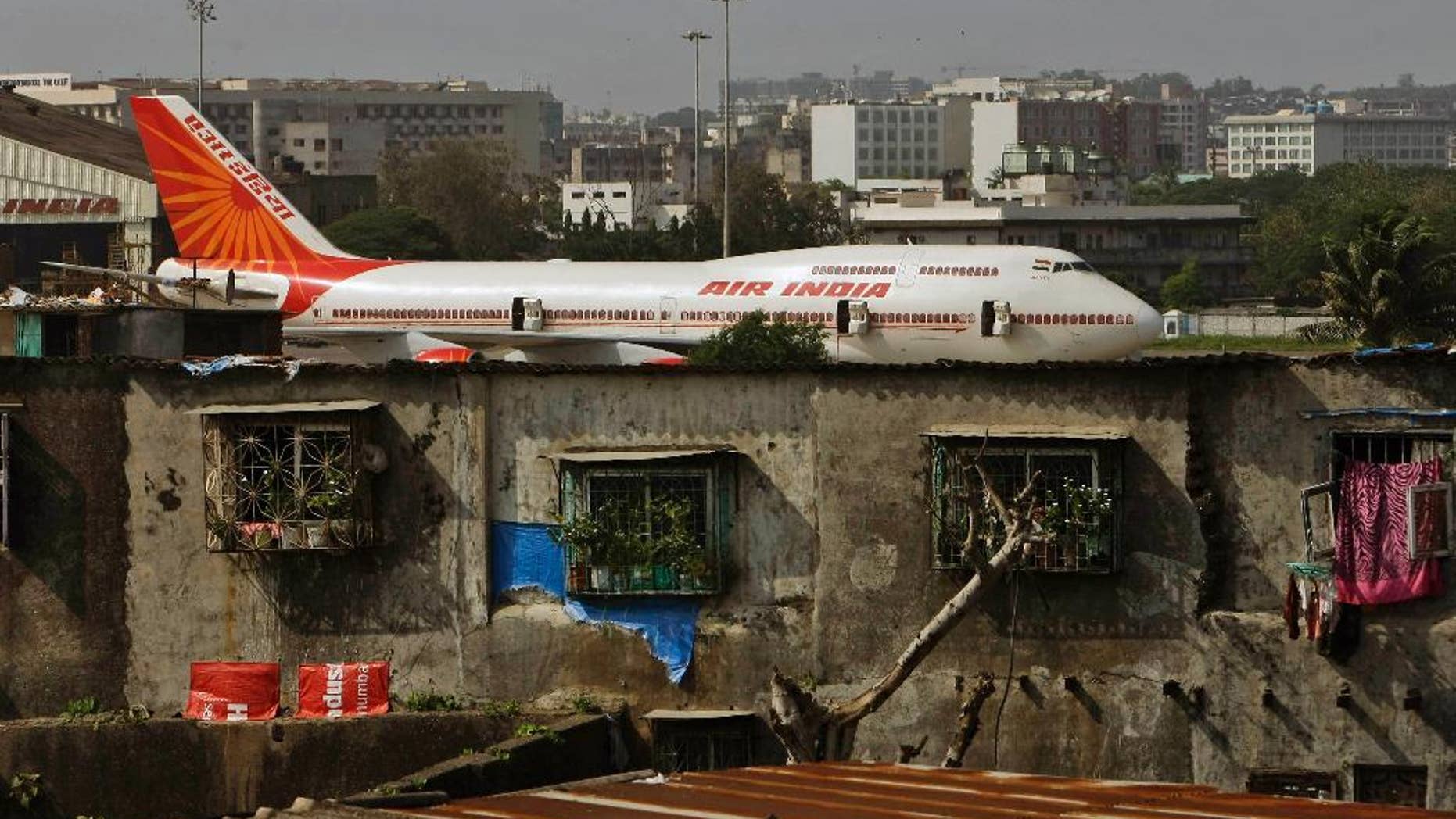 FILE- In this May 25, 2010 file photo, an Air India plane is seen in the background of slums adjoining the the international airport in Mumbai, India. Air India says it has set a world record by flying around the world with an all-female crew. Press Trust of India reported that the flight flew over the Pacific Ocean from New Delhi to San Francisco on Monday, and then flew back to New Delhi over the Atlantic on Friday. (AP Photo/Rajanish Kakade, file)