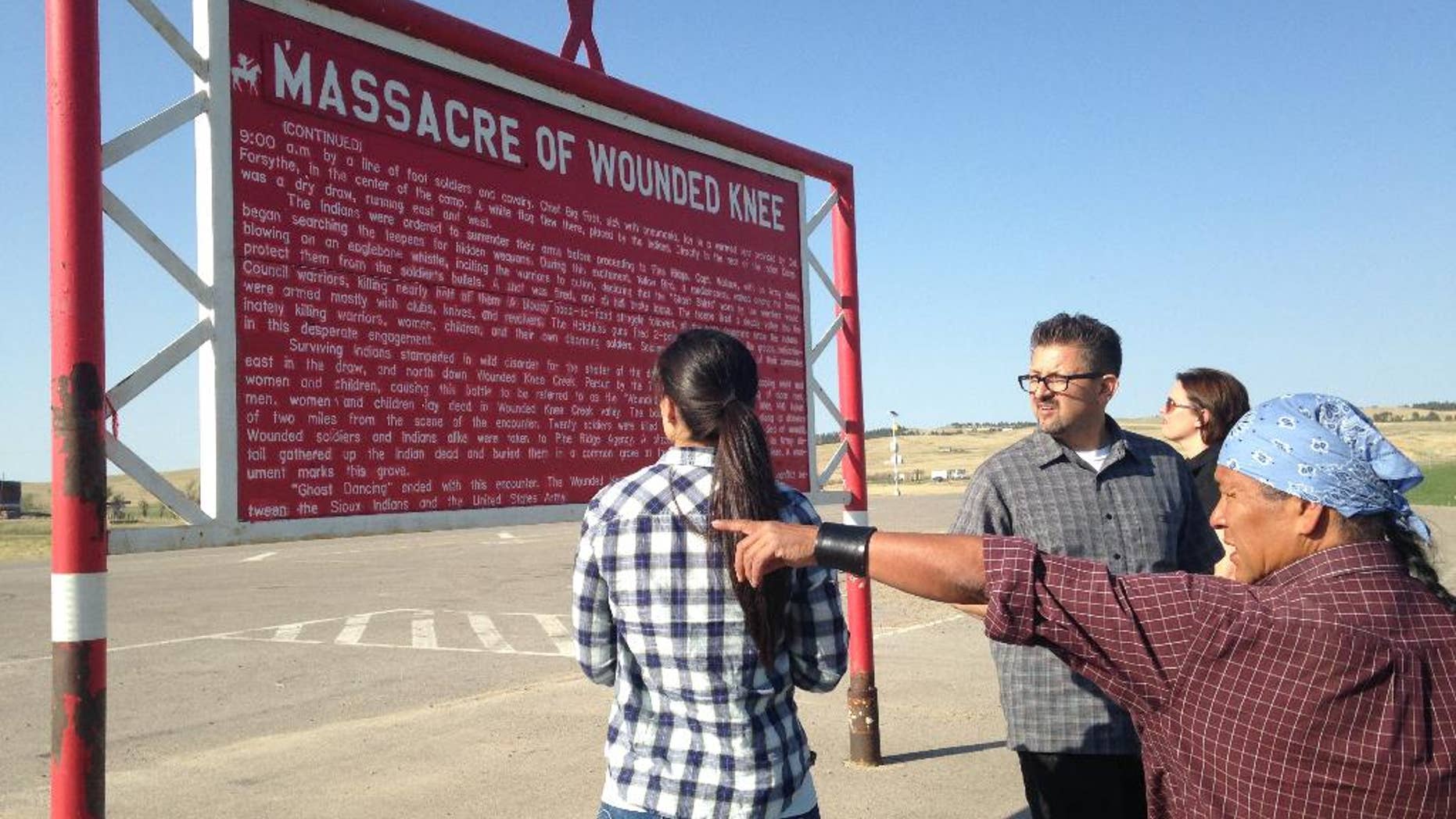 In this May 1, 2015 photo, Native American cartoonist Ricardo Cate', far right, and Chicano cartoonist Lalo Alcaraz, third right, visit Wounded Knee Memorial at Wounded Knee, S.D., on the Pine Ridge Indian Reservation. The nightclub attack in Orlando was initially described by some news organizations, including The Associated Press, as the deadliest mass shooting in U.S. history. In truth, America has seen even bigger massacres, some involving hundreds of men, women and children, like the one at Wounded Knee in 1890 against the Lakota. (AP Photo/Russell Contreras)