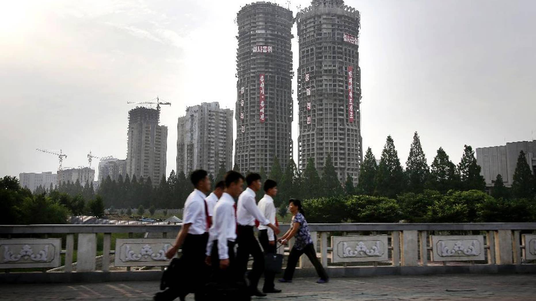 June 27, 2016: North Korean men and women walk past buildings under construction on “Ryomyong Street,” in Pyongyang, North Korea.