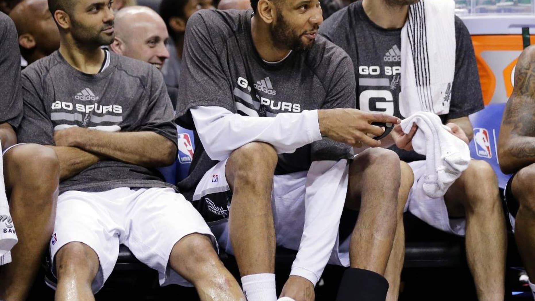 San Antonio Spurs' Tony Parker, left, of France, Tim Duncan, center, and Manu Ginobili, right, sit on the bench during the second half of Game 1 of a Western Conference semifinal NBA basketball playoff series against the Portland Trail Blazers, Tuesday, May 6, 2014, in San Antonio. San Antonio won 116-92. (AP Photo/Eric Gay)
