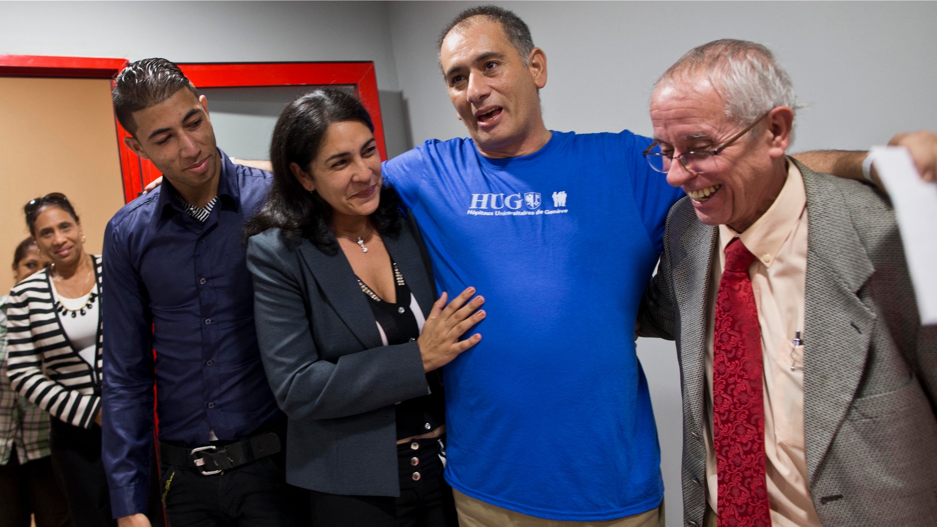 Cuban doctor Felix Baez Sarria, who contracted Ebola while on an aid mission in Sierra Leona, second from right, smiles as he poses for photos with his wife Vania Ferre, son Alejandro Felix, left, and Dr. Jorge Perez upon arrival to Havana, Cuba, Saturday, Dec. 6, 2014. Baez, 43, is among 165 Cuban medical personnel sent to Sierra Leone to fight the disease. He showed symptoms of Ebola on Nov. 16 and was brought to Switzerland for treatment with the experimental drug ZMapp. (AP Photo/Ramon Espinosa, Pool)