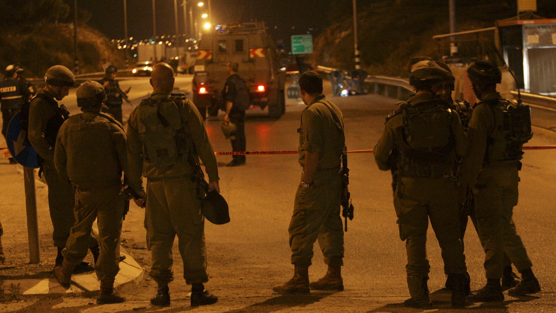 Israeli soldiers stand at the scene of a shooting at a checkpoint in the West Bank near Nablus, Thursday, Nov. 7, 2013. The Israeli military says soldiers shot a Palestinian man to death after he fired an "improvised weapon" at a bus stop in the West Bank. Israeli police said he was launching fireworks. (AP Photo / Nasser Ishtayeh)