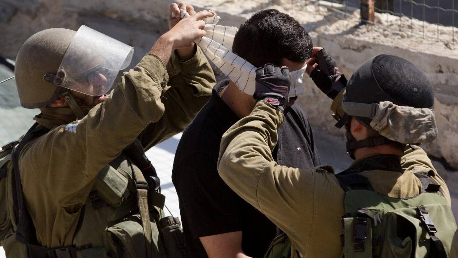 Israeli troops arrest a Palestinian during clashes after the funeral of Ibrahim Awad, 28, in the village of Beit Ummar near the West Bank city of Hebron, Thursday, Sunday, Oct. 11, 2015. Awad died of his wounds on Saturday after being shot by Israeli troops during a protest last week. (AP Photo/Majdi Mohammed)