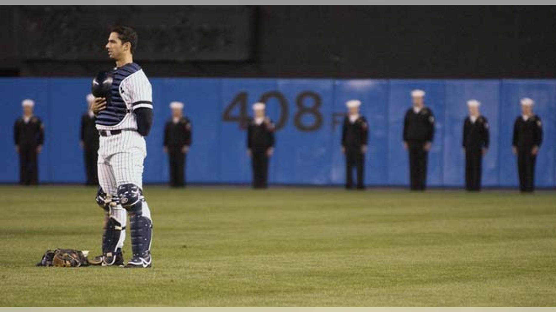 NEW YORK - OCTOBER 11: Yankees catcher Jorge Posada #20 stands in the outfield as a color guard displays a large American flag prior to Game two of the American League Divisional Series between the Oakland Athletics and the New York Yankees October 11, 2001 at Yankee Stadium in the Bronx, New York. The A's won 2-0. (Photo by M. David Leeds/Getty Images)