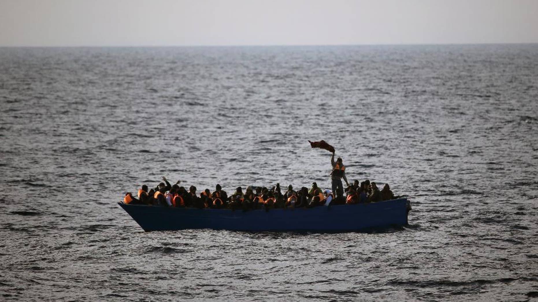 FILE- In this Friday, Feb. 3, 2017 file photo, migrants and refugees wave for help from inside a wooden boat 21 miles north of Sabratha, Libya. The chief of the European border and coast guard agency says migrant deaths in the Mediterranean on the Libya-to-Italy smuggling route have increased to a record level despite ever more rescue vessels trying to prevent mass drownings. (AP Photo/Emilio Morenatti, File)
