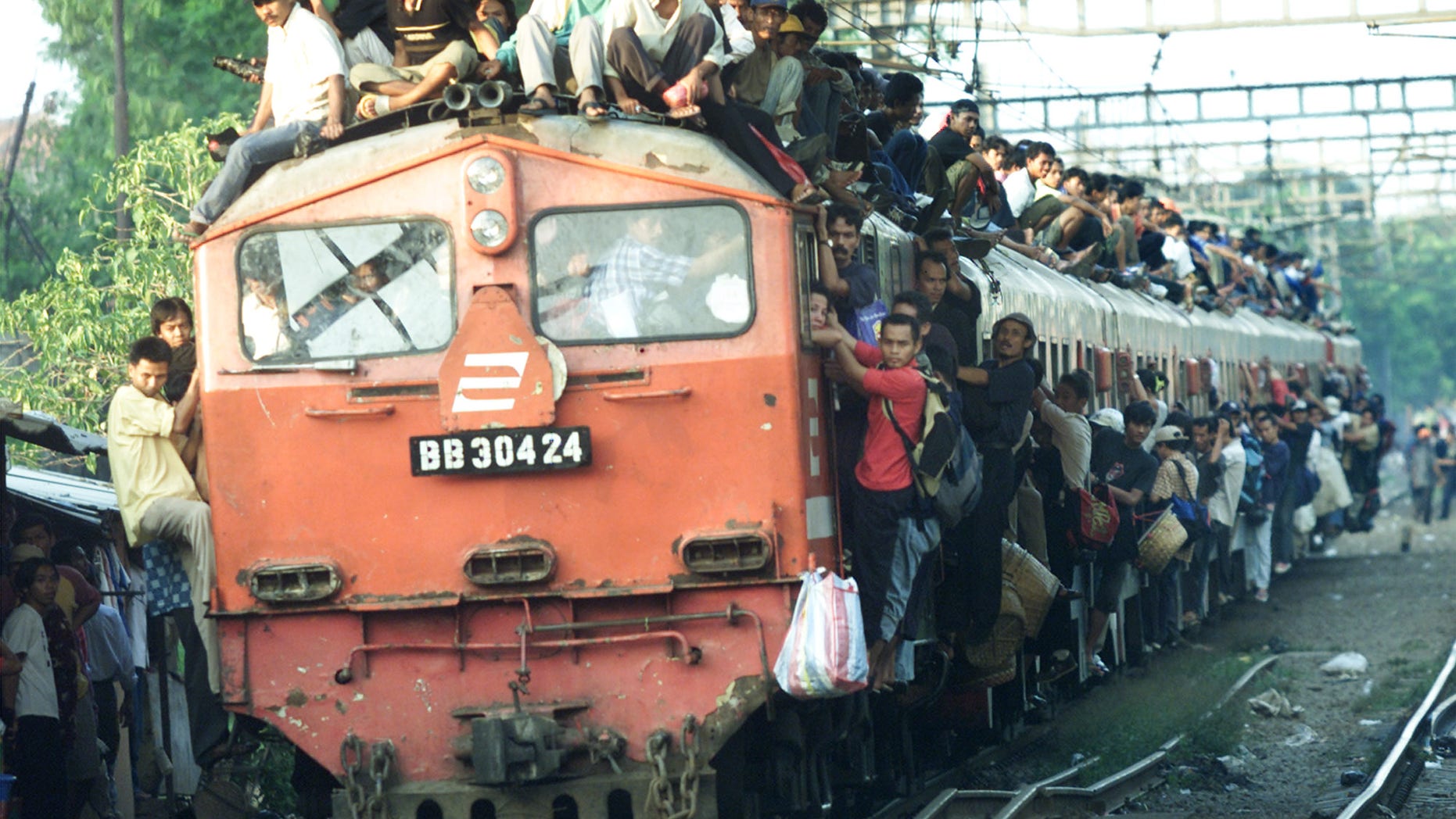 Nov. 12, 2004: Indonesian men hold on to the rooftop and outside of a train bound for Banten province. Indonesia has gone to imaginative extremes to try to stop commuters from riding the roofs of trains by suspending rows of grapefruit-sized concrete balls above railway lines a few inches above the tops of carriages at points where trains enter or pull out of stations, or where they go through crossings.