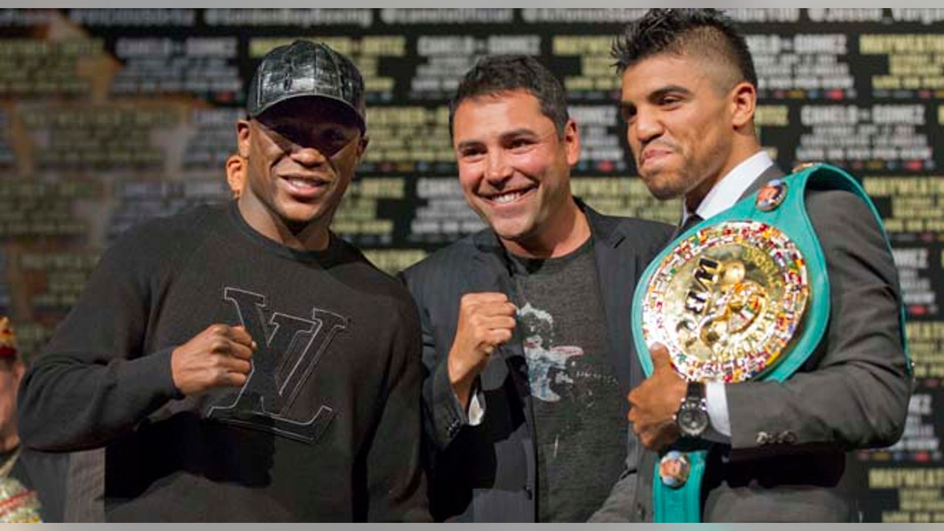 September 14, 2011: Floyd Mayweather, left, and Victor Ortiz, right, pose for a photo with Oscar De La Hoya after a news conference.