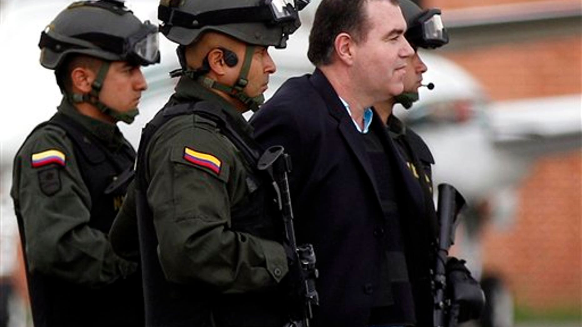 Colombian police officers escort alleged drug trafficker Walid The Turk Makled to a waiting plane at the military airport in Bogota, Colombia, Monday May 9, 2011. The Venezuelan citizen of Syrian descent was arrested late last year on a U.S. warrant in Colombia. Colombia President Juan Manuel Santos said the law favored Makled being sent to Venezuela instead of the U.S. because it was the first country to request his extradition.(AP Photo/Fernando Vergara)