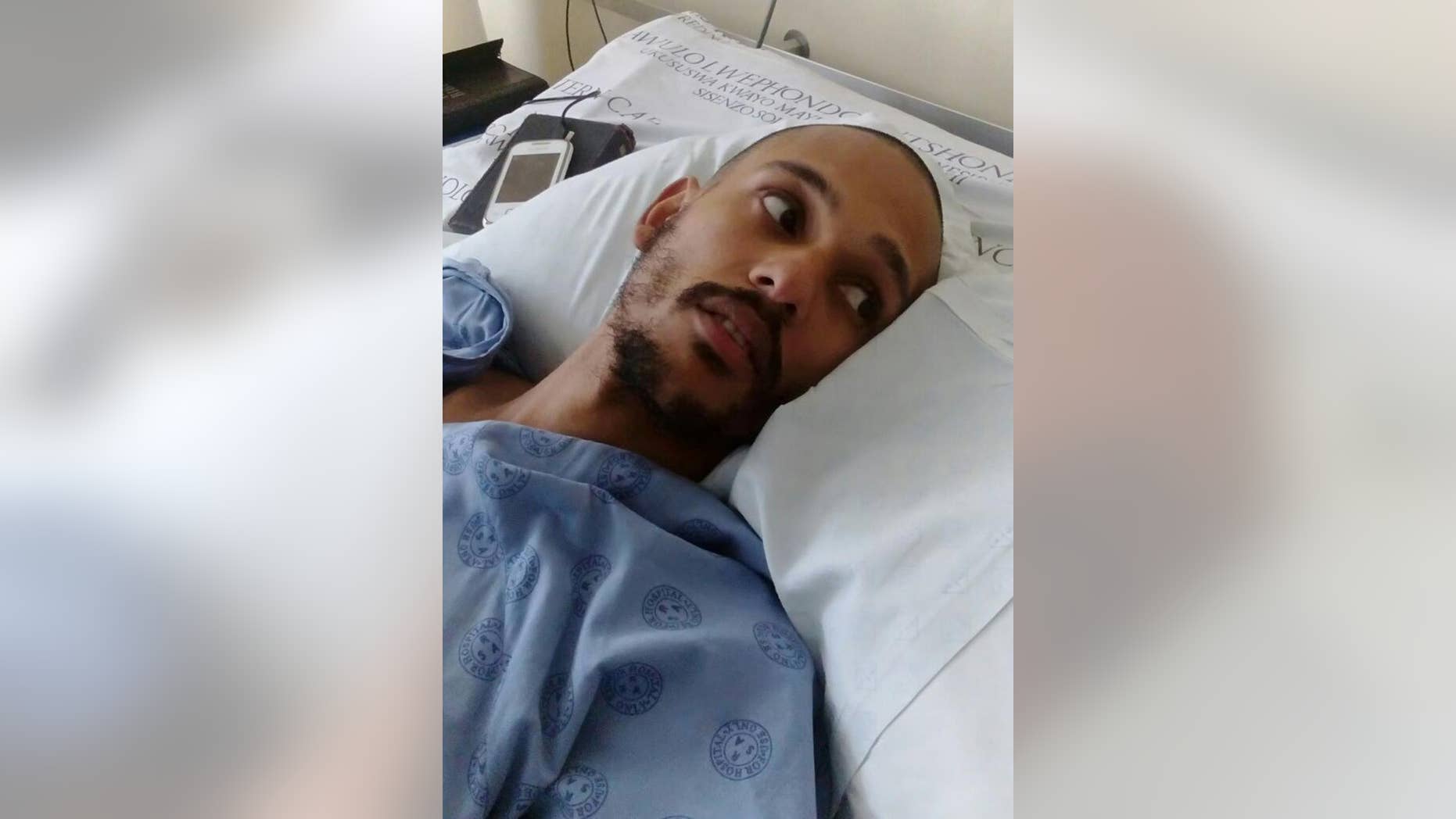 An injured Darryn August lays in his hospital bed in Cape Town, Wednesday, May 11, 2016 after he was thrown from a moving train by assailants last week. He is now paralyzed from the waist down, prompting a flow of donations for what is expected to be a long, costly rehabilitation. (AP Photo/Edwin Brooks)