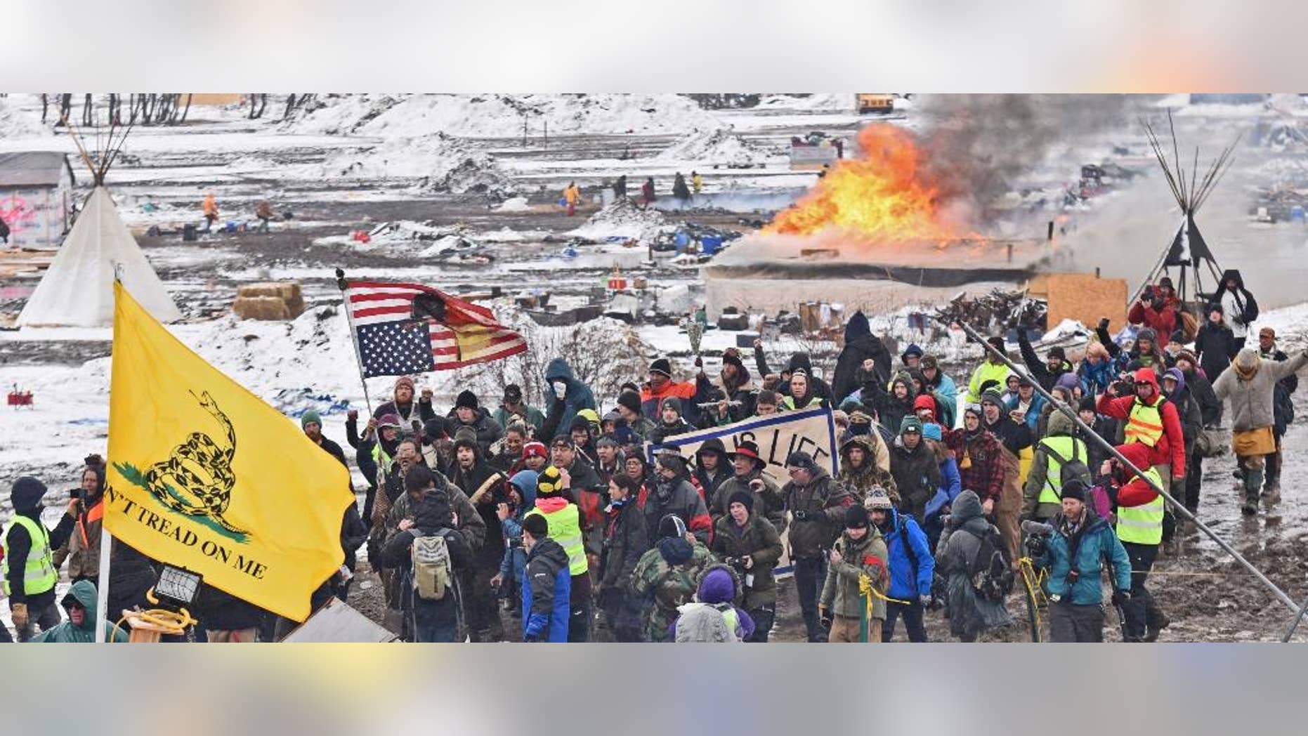 FILE - In this Feb. 22, 2017, file photo, a fire set by protesters burns in the background as opponents of the Dakota Access pipeline leave their main protest camp Wednesday near Cannon Ball, N.D. A federal judge will hear arguments Tuesday, Feb. 28, 2017, about whether to stop the final bit of construction on the disputed Dakota Access pipeline, perhaps just days before it could start moving oil.(Tom Stromme/The Bismarck Tribune via AP, File)
