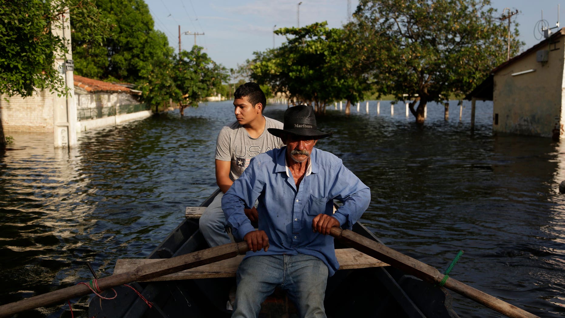 Victor Ferreira, displaced by flooding, rows through the streets in Asuncion, Paraguay, Wednesday, Dec. 23, 2015.