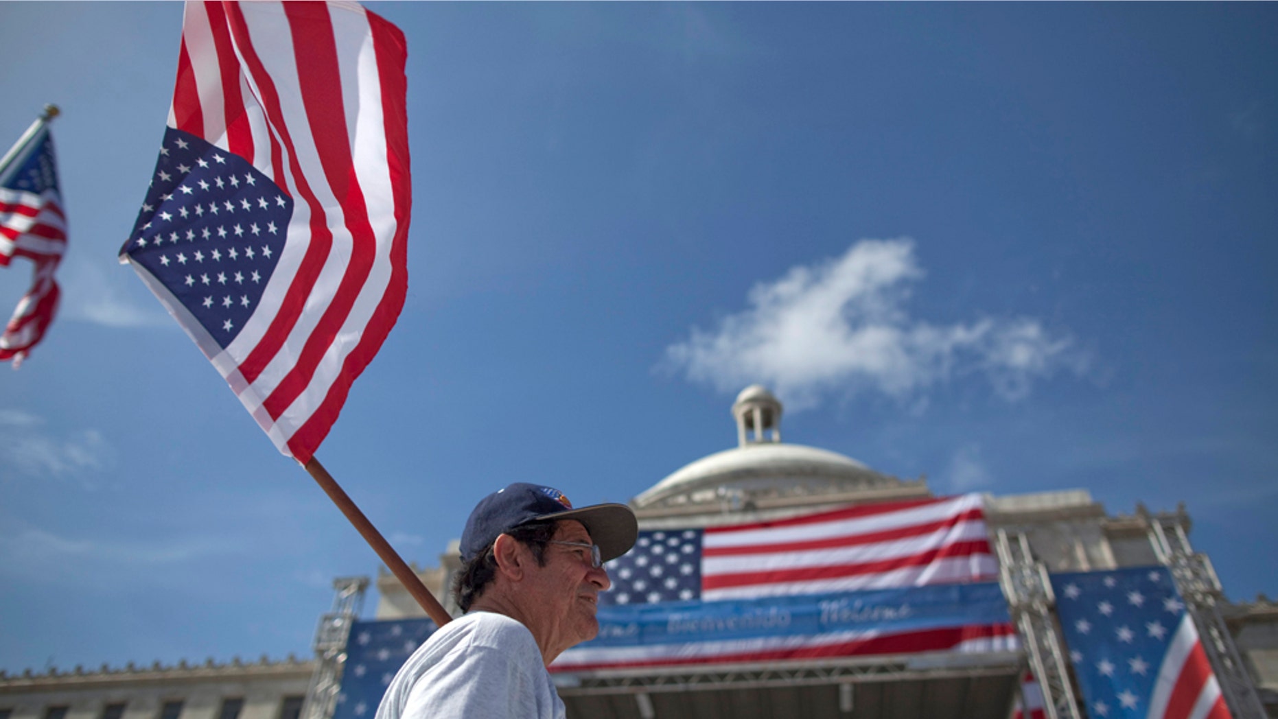 A man walks holding a US flag in front of the Capitol before the arrival of President Barack Obama in San Juan, Puerto Rico, Tuesday June 14, 2011. Obama's trip marks the first visit to Puerto Rico by a sitting U.S. President since John F. Kennedy's 1961 visit. (AP Photo/Ramon Espinosa)