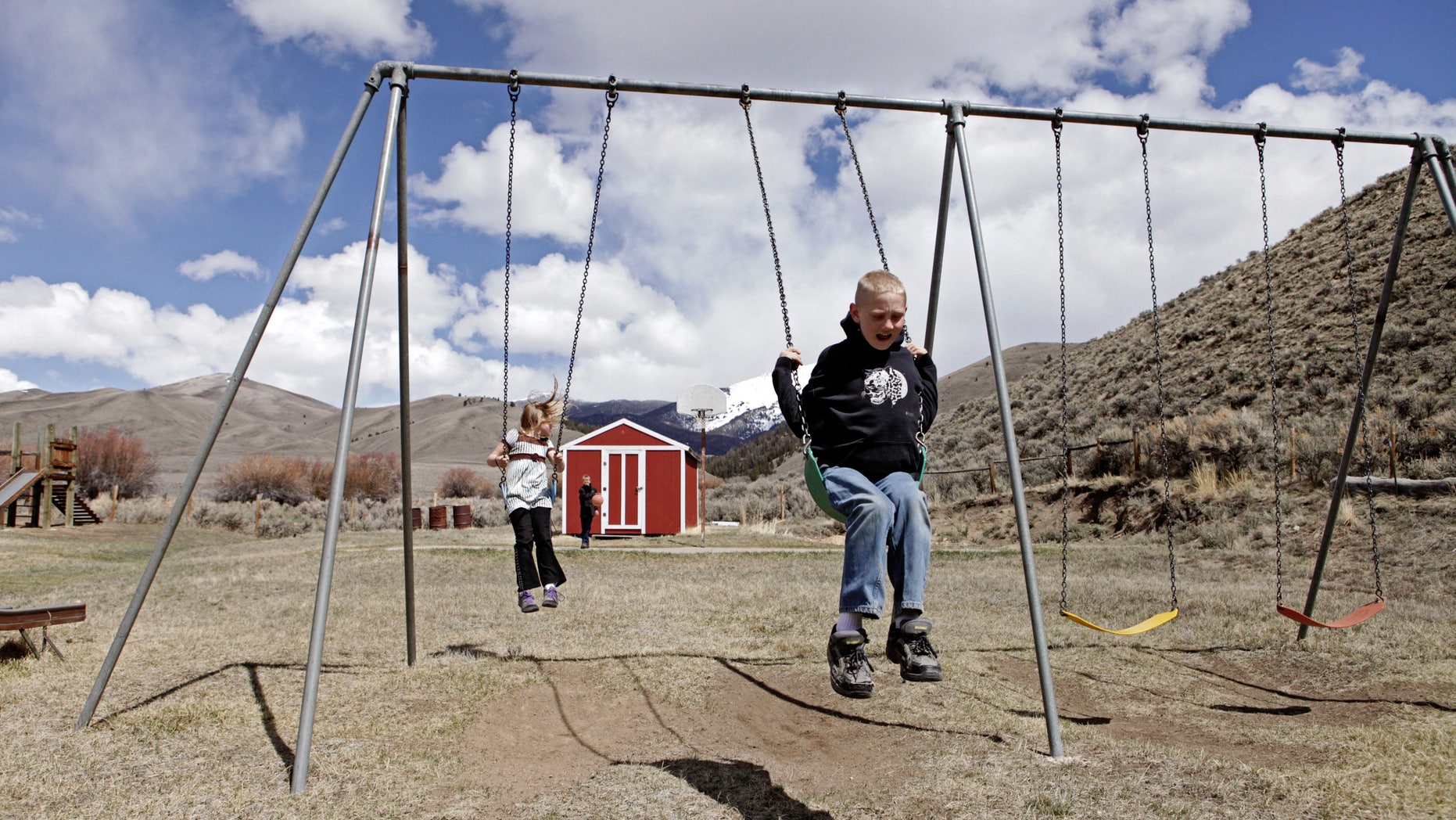 In this April 30, 2013 , photo, siblings, Tyrell and Shelby Schrepfer swing at recess in Polaris, Montana. The pair are students at Polaris School, which only serves four students. (AP Photo/Kathryn Haake)