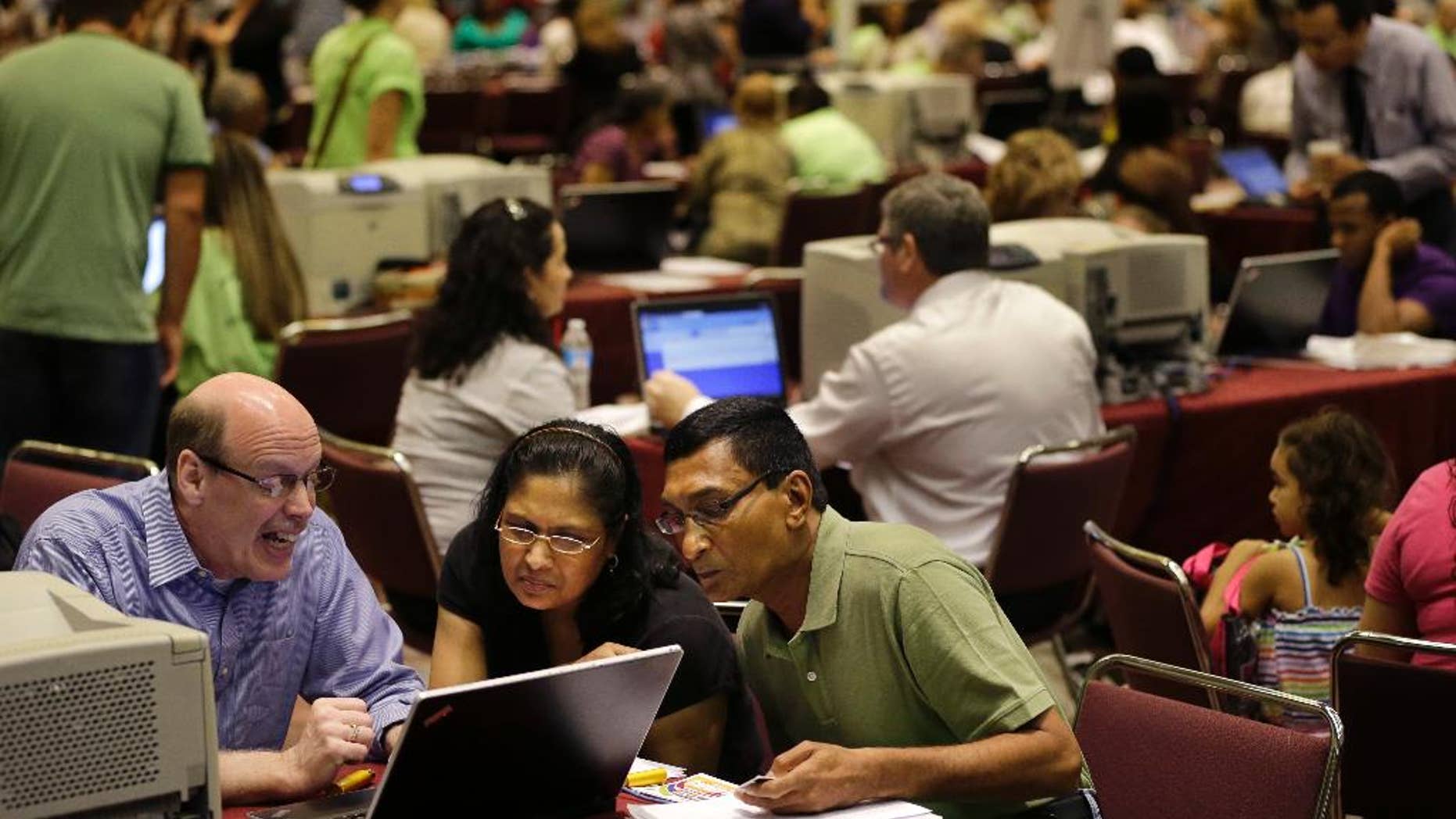 FILE - In this Sept. 3, 2014 file photo, former Revel Hotel Casino employees, Jignasha Shah, 45, center, and Ranjitsinh Rana, 56, right, get help from John McCaffery, as they and thousands of other newly laid-off casino workers file for unemployment benefits at the Atlantic City Convention Center in Atlantic City, N.J. The government reports on state unemployment rates for August on Friday, Sept. 19, 2014. (AP Photo/Mel Evans, File)