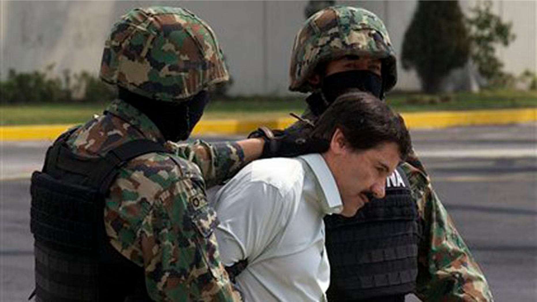 Joaquin "El Chapo" Guzman is escorted to a helicopter in handcuffs by Mexican navy marines at a navy hanger in Mexico City, Mexico, Saturday, Feb. 22, 2014.