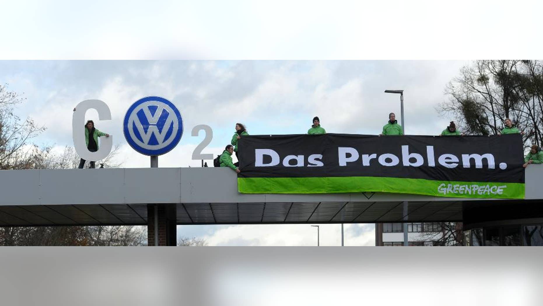 Greenpeace activists stand with 'CO2' formed with the VW logo and a banner that reads 'the problem' above the Volkswagen factory gate in Wolfsburg, Germany, Monday, Nov. 9, 2015. (Peter Steffen/dpa via AP)