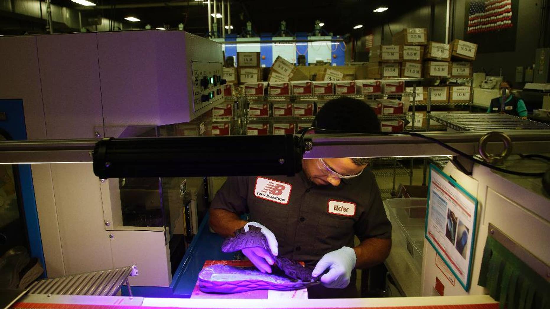 FILE - In this July 1, 2015 file photo, Elder Brandao, working under ultraviolet lights, glues an outsole to a midsole of the New Balance proposed 950v2 sneaker, that has passed military testing, at one of company's manufacturing facilities in Boston. The Institute for Supply Management, a trade group of purchasing managers, issues its index of manufacturing activity for August on Tuesday, Sept. 1, 2015. (AP Photo/Stephan Savoia, File)