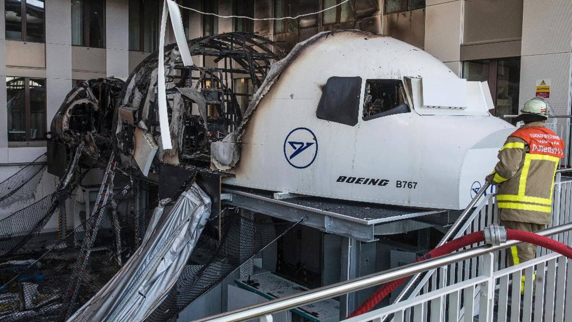 A firefighter stands in the office of Condor airlines next to a burned out flight simulator in the airport in Frankfurt am Main, Germany, Thursday Dec. 29, 2016. The flight simulator has caught fire in an office block at Frankfurt airport, forcing some 200 people to leave the building. The fire service says one person was taken to a hospital suffering from the effects of smoke inhalation. (Frank Rumpenhorst/dpa via AP)