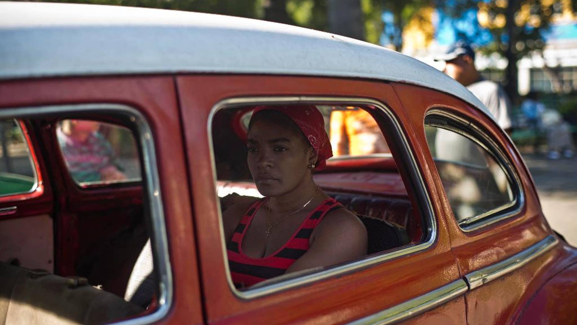 A woman waits in a classic American car that's used as a shared taxi by commuters in Havana, Cuba, early Thursday, Dec. 18, 2014. After a half-century of Cold War acrimony, the United States and Cuba abruptly moved on Wednesday to restore diplomatic relations _ a historic shift that could revitalize the flow of money and people across the narrow waters that separate the two nations. (AP Photo/Ramon Espinosa)