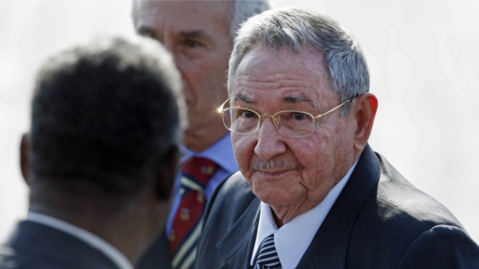 Flanked by a bodyguard, left, and a diplomatic protocol officer, Cuba's President Raul Castro makes his way to a waiting car after arriving at the Arturo Merino Benitez International Airport in Santiago, Chile, Friday, Jan. 25, 2013. Castro along with other Latin American, Caribbean and European leaders are gathering in Santiago for this weekend's CELAC-EU economic summit. (AP Photo/Luis Hidalgo)
