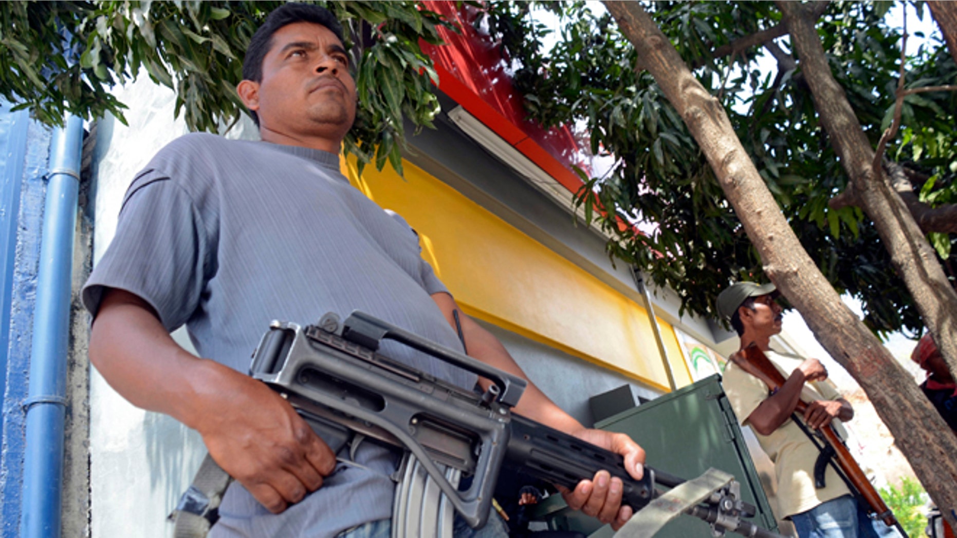 A group of armed vigilantes stand at the entrance to the town of Tierra Colorada, Mexico, Wednesday, March 27, 2013. Hundreds of armed vigilantes have taken control of this town on a major highway in the Pacific coast state of Guerrero, arresting local police officers and searching homes after a vigilante leader was killed. Several opened fire on a car of Mexican tourists headed to the beach for Easter week. (AP Photo/Bernandino Hernandez)