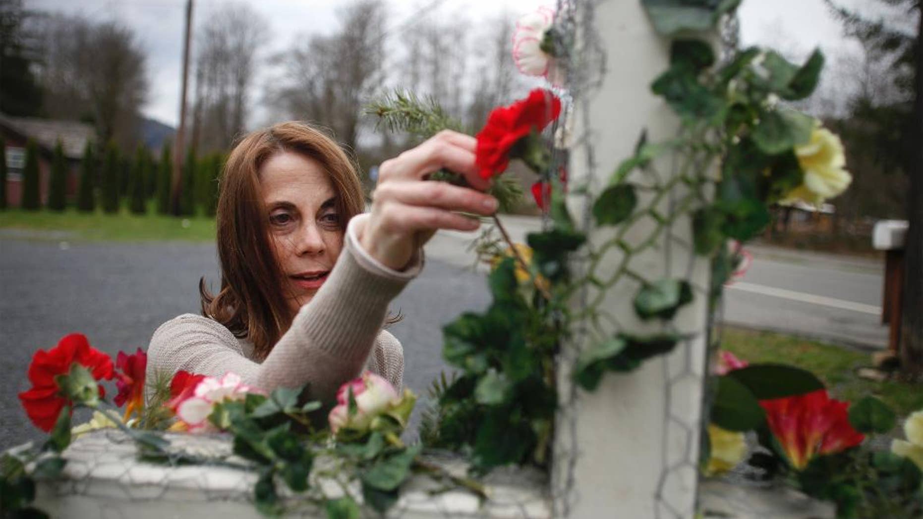 Tina Ray puts flowers on a cross in dedication of the mudslide victims at the Oso Community Chapel Wednesday, Mar. 26, 2014, in Oso, Wash. Tina and her husband, Pastor Gary Ray, run the Oso Community Chapel and are providing a place for victims and family members to come pray. (AP Photo/The Herald, Sofia Jaramillo)