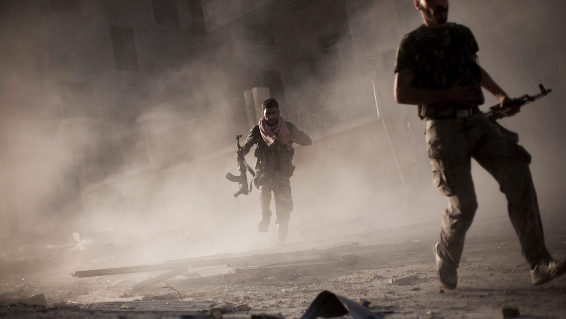 Sept. 7, 2012: In this photo, Free Syrian Army fighters run after attacking a Syrian Army tank during fighting in the Izaa district in Aleppo, Syria.