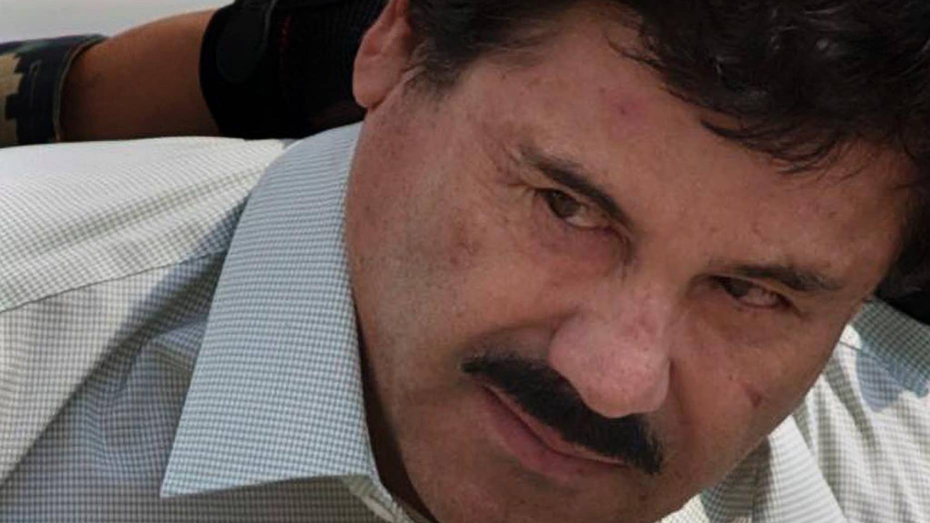 FILE - In this Feb. 22, 2014 file photo, Joaquin "El Chapo" Guzman is escorted to a helicopter in handcuffs by Mexican navy marines at a navy hanger in Mexico City. Mexico’s national security commissioner says the jailed drug lord could be extradited to the United States by early next year. Renato Sales tells Televisa it could happen “in January or February.” A lawyer for Guzman said recently that there there could be a court decision on extradition around the end of the year, but either side would then be able to appeal. (AP Photo/Eduardo Verdugo, File)