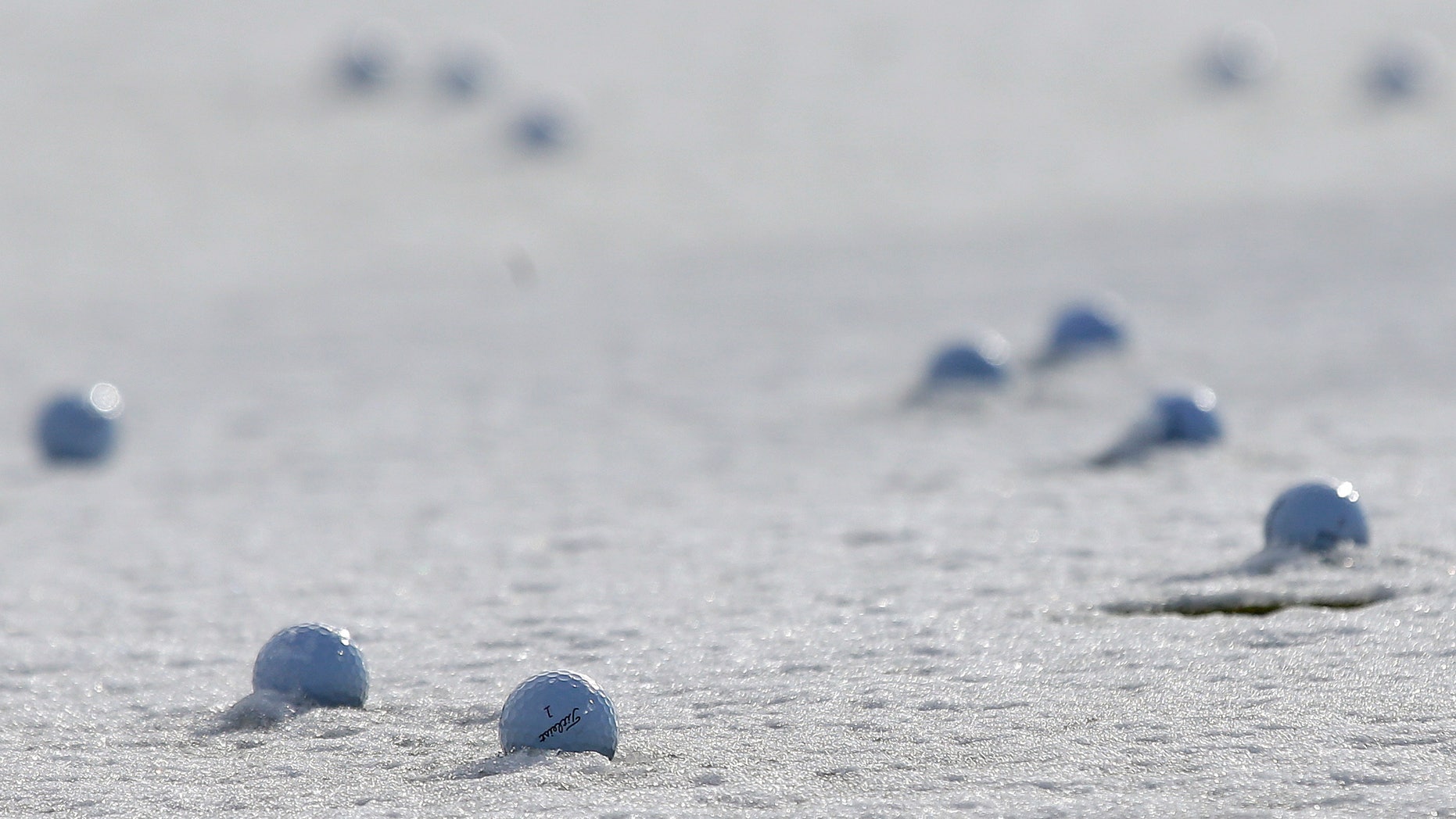 Practice balls sit in frozen snow on the practice range before play resumes for the first round of the Match Play Championship golf tournament, Thursday, Feb. 21, 2013, in Marana, Ariz. A snow storm blanketed the course on Wednesday suspending the first round of play and postponing it until late Thursday morning. (AP Photo/Ted S. Warren)