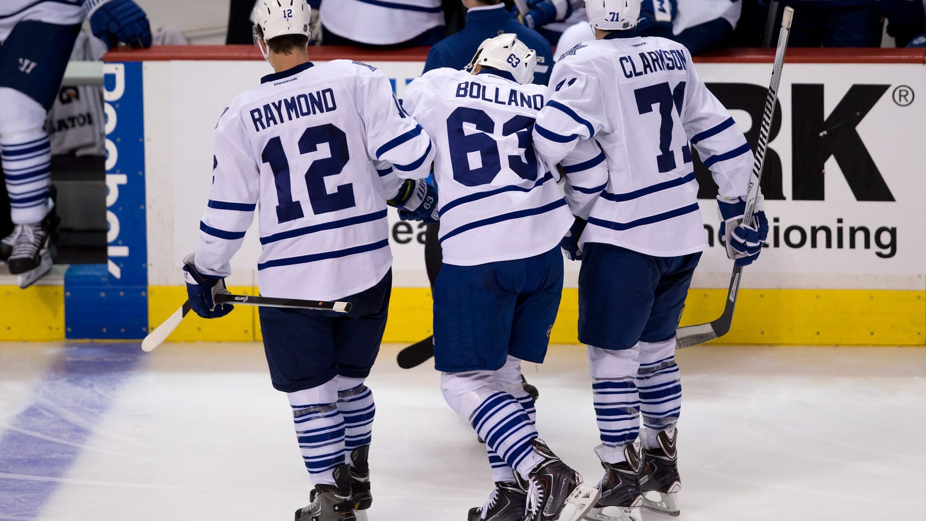 Toronto Maple Leafs' Dave Bolland, center, is helped off the ice by Mason Raymond, left, and David Clarkson during the second period of an NHL hockey game against the Vancouver Canucks in Vancouver, British Columbia, on Saturday, Nov. 2, 2013. (AP Photo/The Canadian Press, Darryl Dyck)