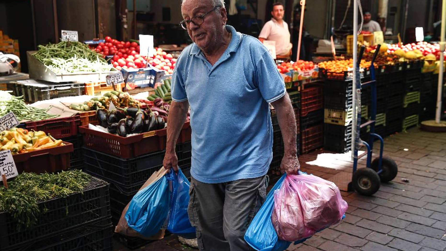A man carries goods at a central market in Athens, Greece, Wednesday, June 17, 2015. Athens must pay 1.6 billion euros ($1.8 billion) off its debts at the end of the month to avoid a possible default and secure its cherished place among the 19 countries using the single currency for a little longer. (AP Photo/Yorgos Karahalis)
