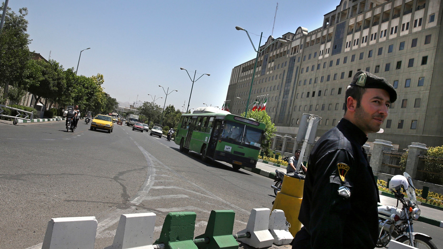 A police officer stands guard as vehicles drive in front of Iran's parliament building in Tehran, Iran, Thursday, May 8, 2017.
