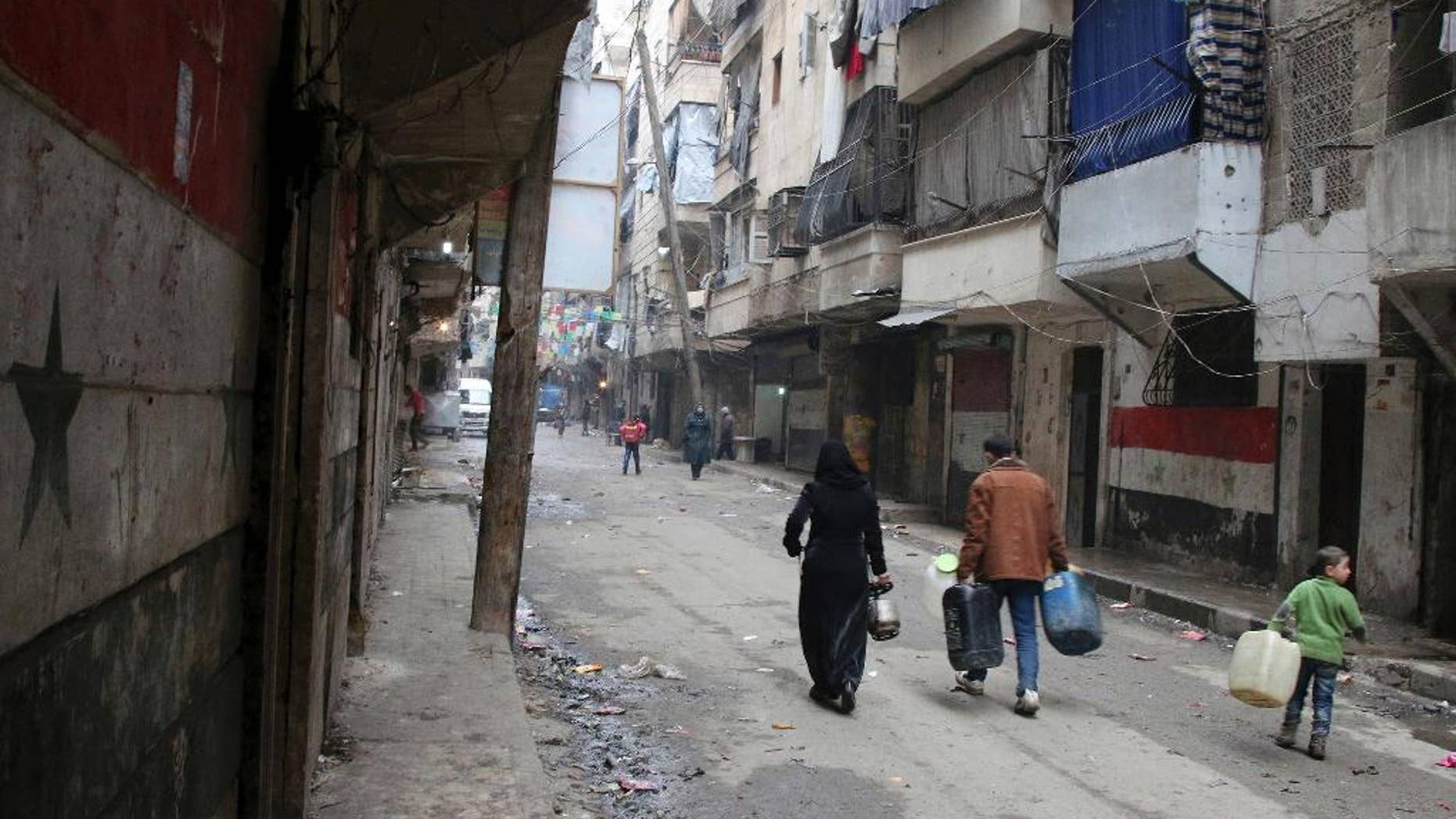 FILE - In this Feb. 11, 2016, file photo, civilians walk with containers for fuel and water in Aleppo, Syria. Syrian rescue worker says three civilians, a mother and two children, died in a suspected chlorine gas attack on an opposition-held district in the city of Aleppo. The report, which was posted online on Thursday, Aug. 11, could not be independently verified and it was not clear how it was determined that chlorine gas was released. (Alexander Kots/Komsomolskaya Pravda via AP, File)