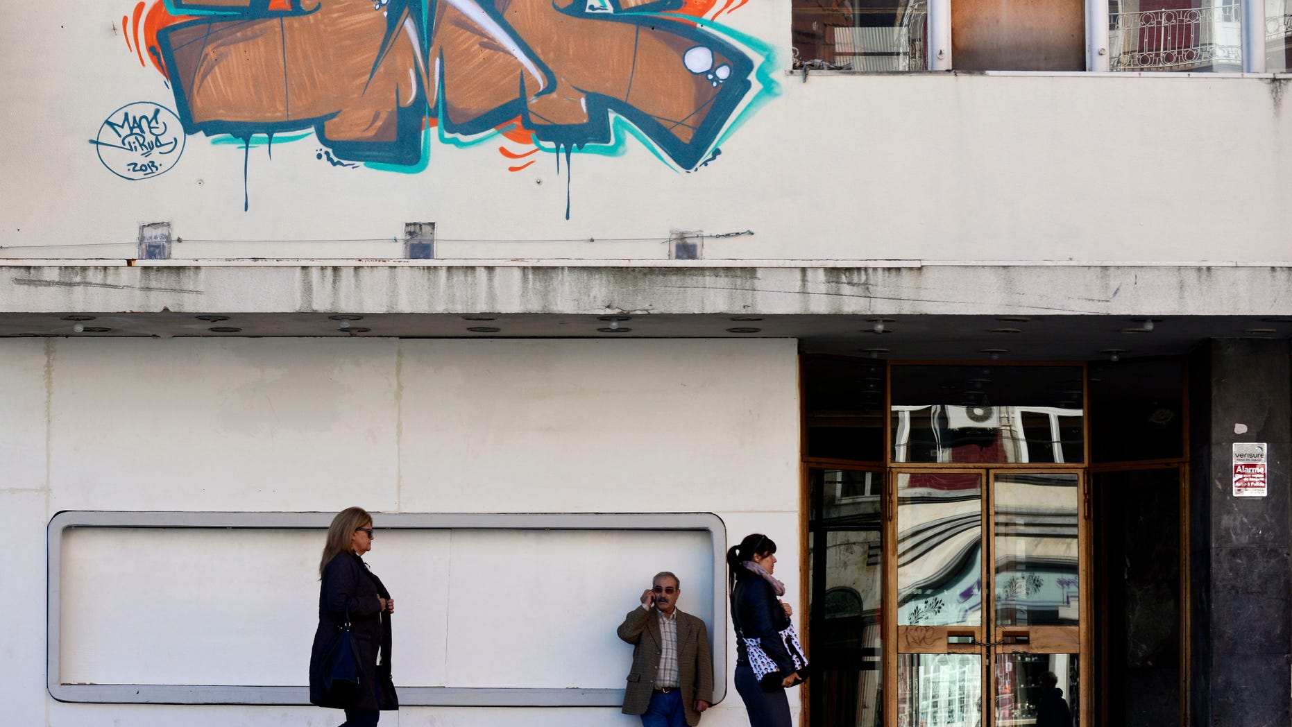 Pedestrians walk by a shuttered Art-Deco cinema and concert venue, Cinema Batalha, in Porto, Portugal, Wednesday, Oct. 30, 2013. Strikes and rallies are expected in the next weeks to protest the austerity measures the Portuguese government has been compelled to adopt in return for a 78 billion euro ($105.6 billion) bailout reached in 2011. (AP Photo/Paulo Duarte)