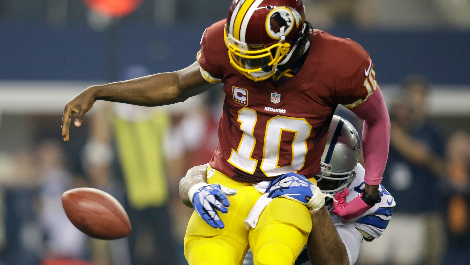 Washington Redskins quarterback Robert Griffin III (10) loses the ball after being sacked by Dallas Cowboys defensive tackle Jason Hatcher in the second half of an NFL football game, Sunday, Oct. 13, 2013, in Arlington, Texas. The Redskins recovered the fumble. (AP Photo/Tim Sharp)