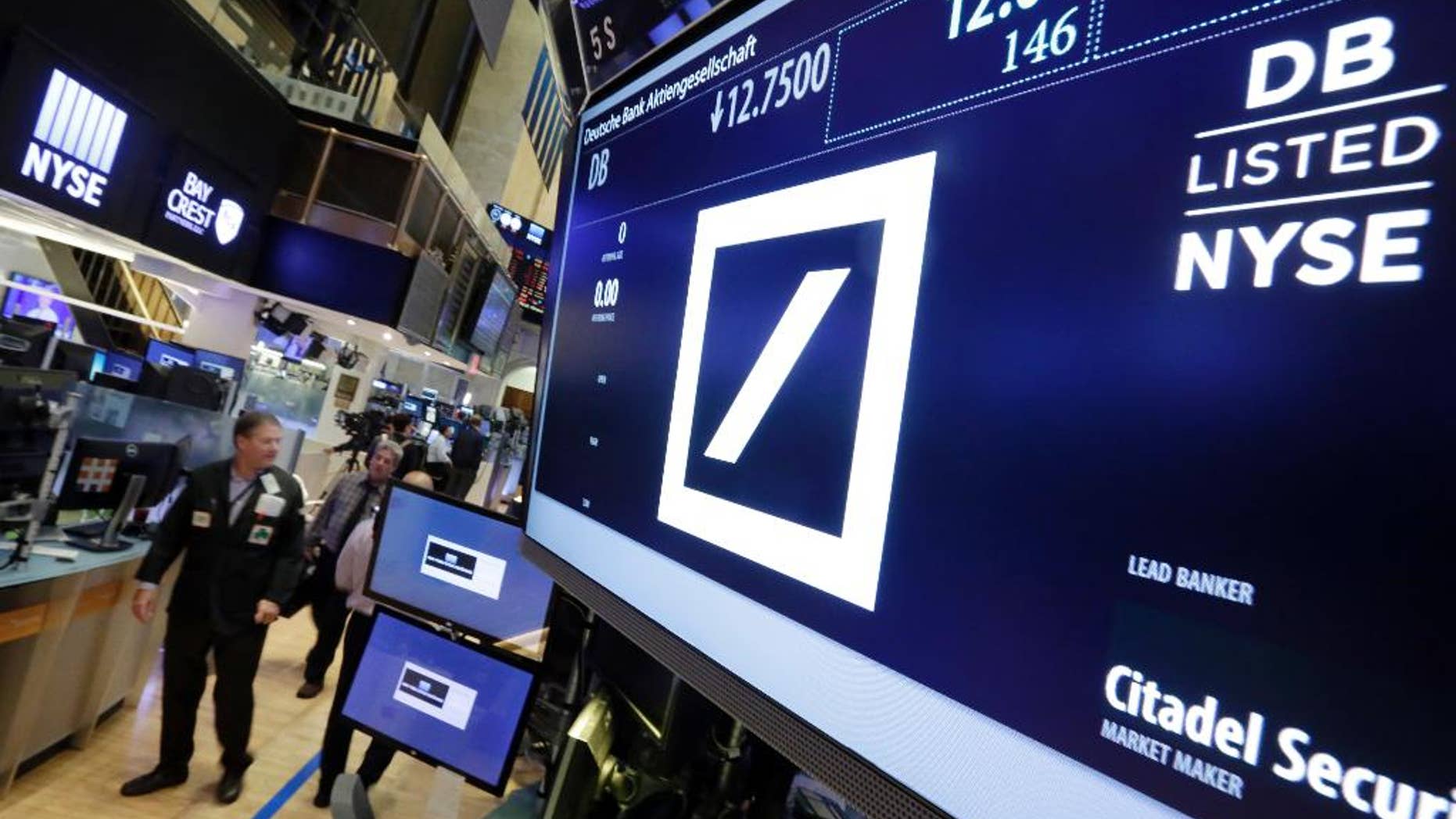 Traders walk by the post where Deutsche Bank is traded on the floor of the New York Stock Exchange, Monday, Sept. 26, 2016. Shares in Deutsche Bank are down sharply after a report that the German government won't intervene with U.S. officials who are pressing the bank to pay $14 billion to settle an investigation into its sales of mortgage-backed securities. (AP Photo/Richard Drew)