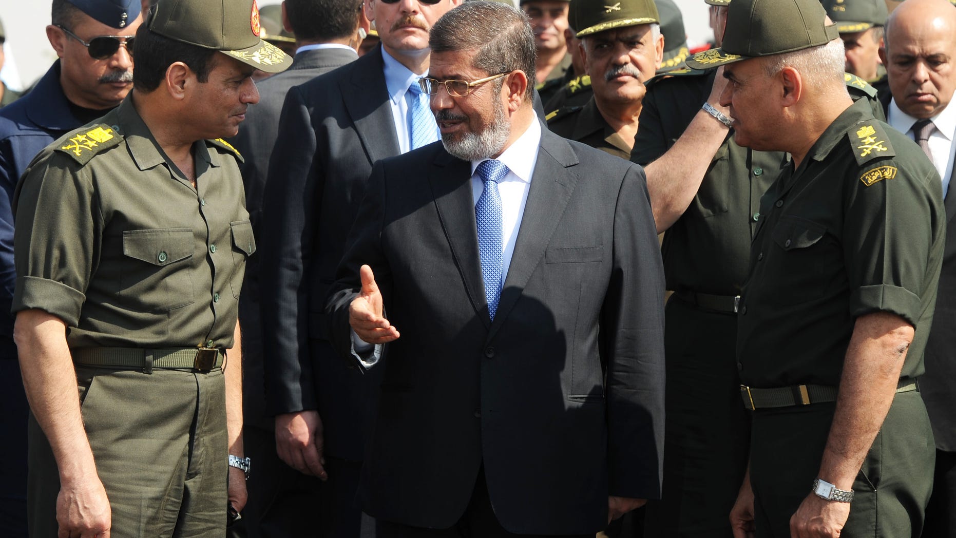 FILE - In this Wednesday, Oct. 10, 2012 file photo released by the Egyptian Presidency, then Egyptian President Mohammed Morsi, center, speaks with Minister of Defense, Lt. Gen. Abdel-Fattah el-Sissi, left, at a military base in Ismailia, Egypt. An Egyptian court has set Nov. 4, 2013, as the start date for the trial of ousted President Mohammed Morsi on charges of incitement to murder for the killings of opponents who were rallying outside his palace while he was in office. Morsi, ousted in a popularly-backed military coup in July, has been held incommunicado since. (AP Photo/Egyptian Presidency)
