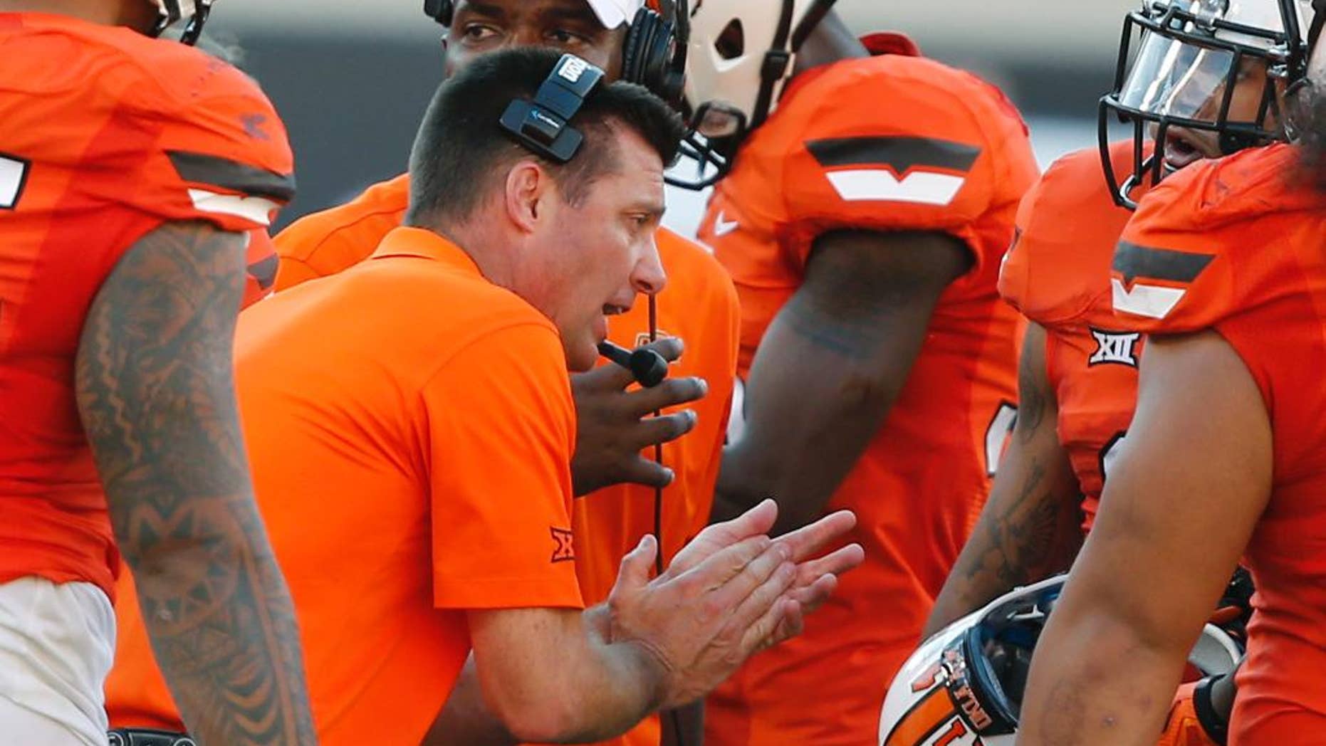 Oklahoma State coach Mike Gundy talks with his team during a timeout in the fourth quarter of an NCAA college football game against West Virginia in Stillwater, Okla., Saturday, Oct. 25, 2014. West Virginia won 34-10. (AP Photo/Sue Ogrocki)