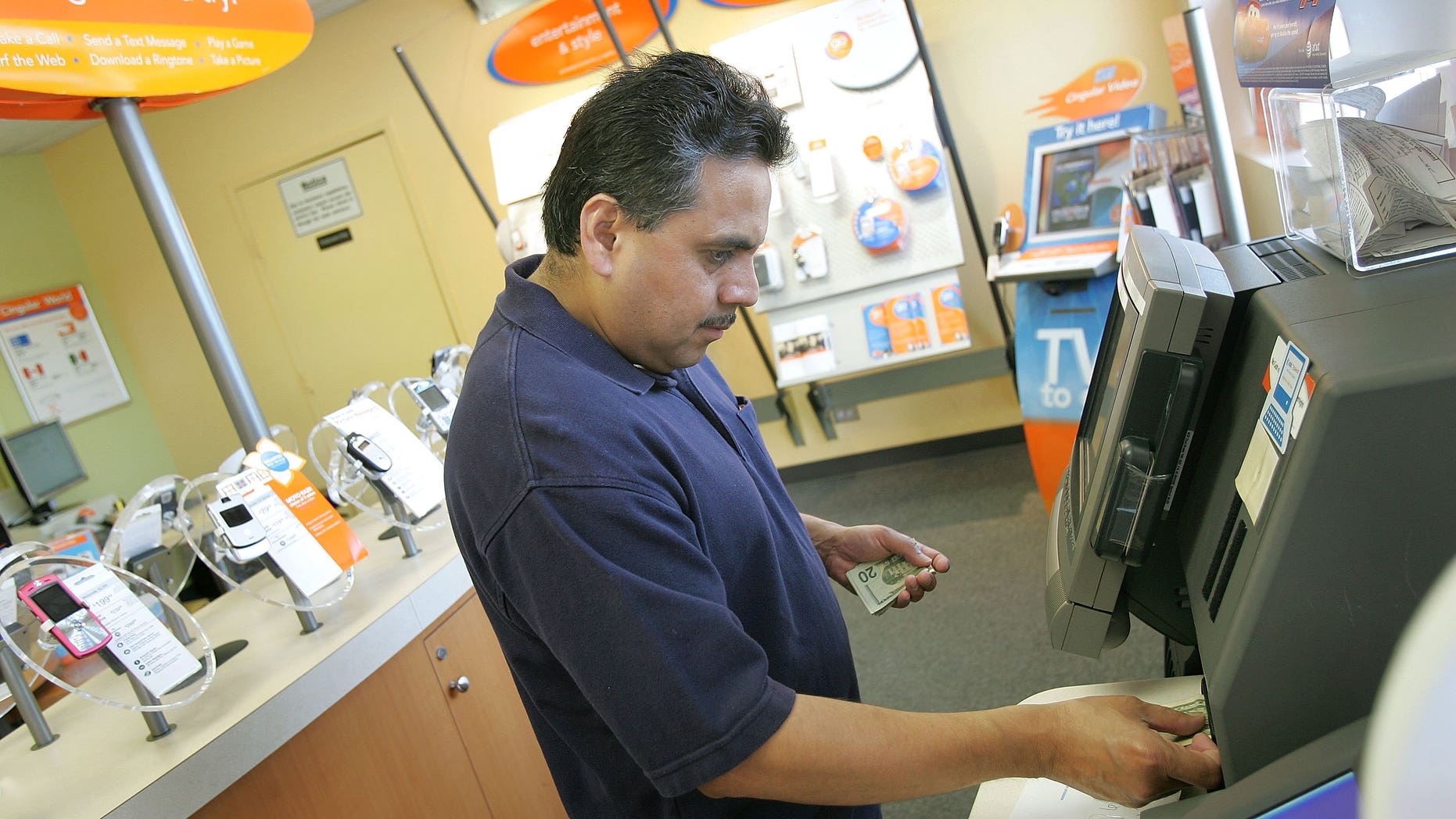ELMHURST, IL - JUNE 12: Mexican-American Alberto Mejia pays his Cingular phone bill at a Cingular store June 12, 2006 in Elmhurst, Illinois. Cingular, the largest wireless carrier in the nation, is reportedly converting 420 of their stores in more than 40 cities in the US to, as Cingular says, "a bilingual concept," in that the stores will have both English and Spanish phone information, payment options and bilingual staff members. This Elmhurst store is one of the converted stores. (Photo by Tim Boyle/Getty Images)
