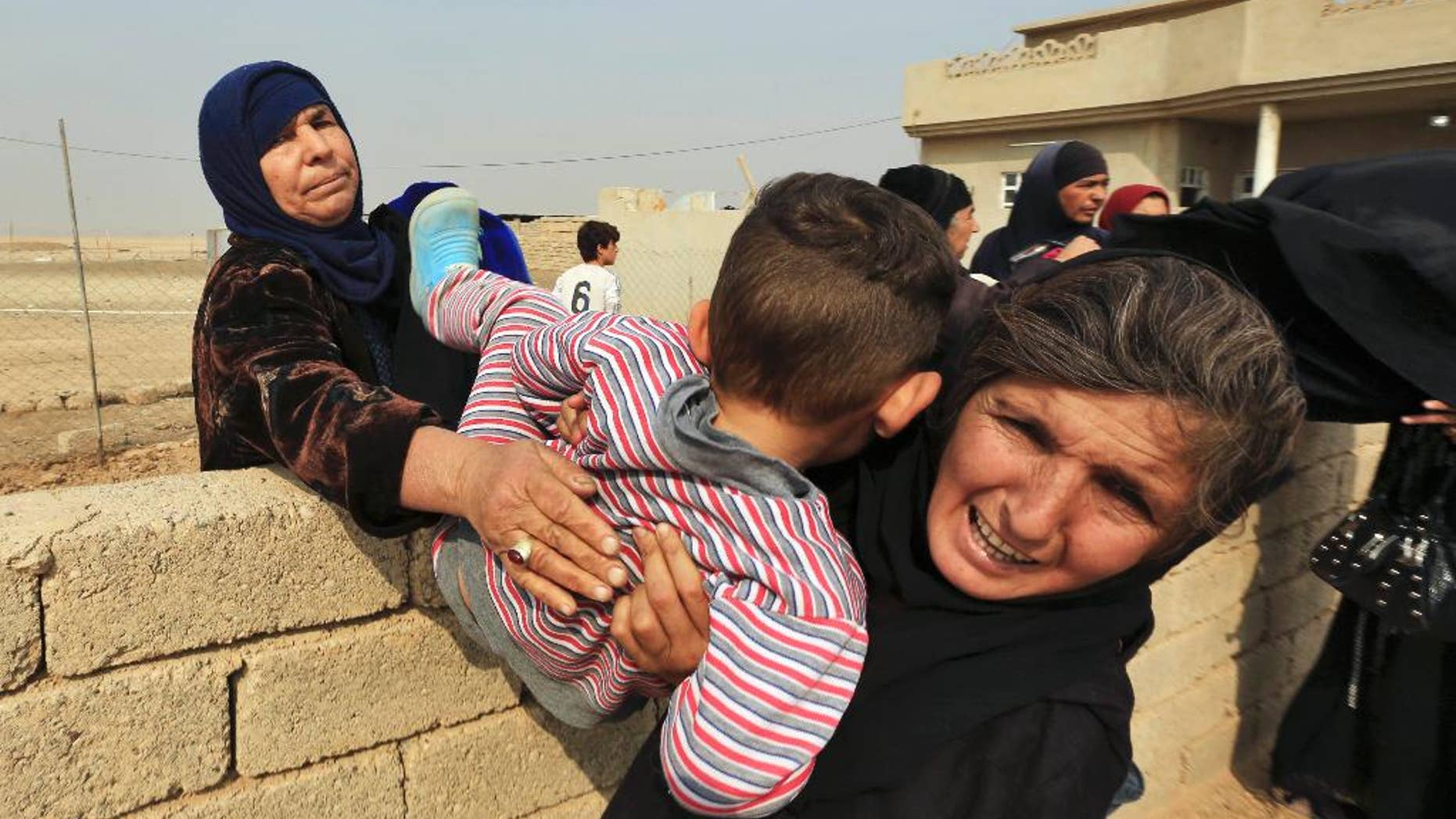 Women carry a boy over a wall as civilians flee their houses in the village of Tob Zawa, Iraq, about 9 kilometers (5.6 miles) from Mosul, Tuesday, Oct. 25, 2016, as Iraq's elite counterterrorism forces fight against Islamic State militants. (AP Photo/Khalid Mohammed)