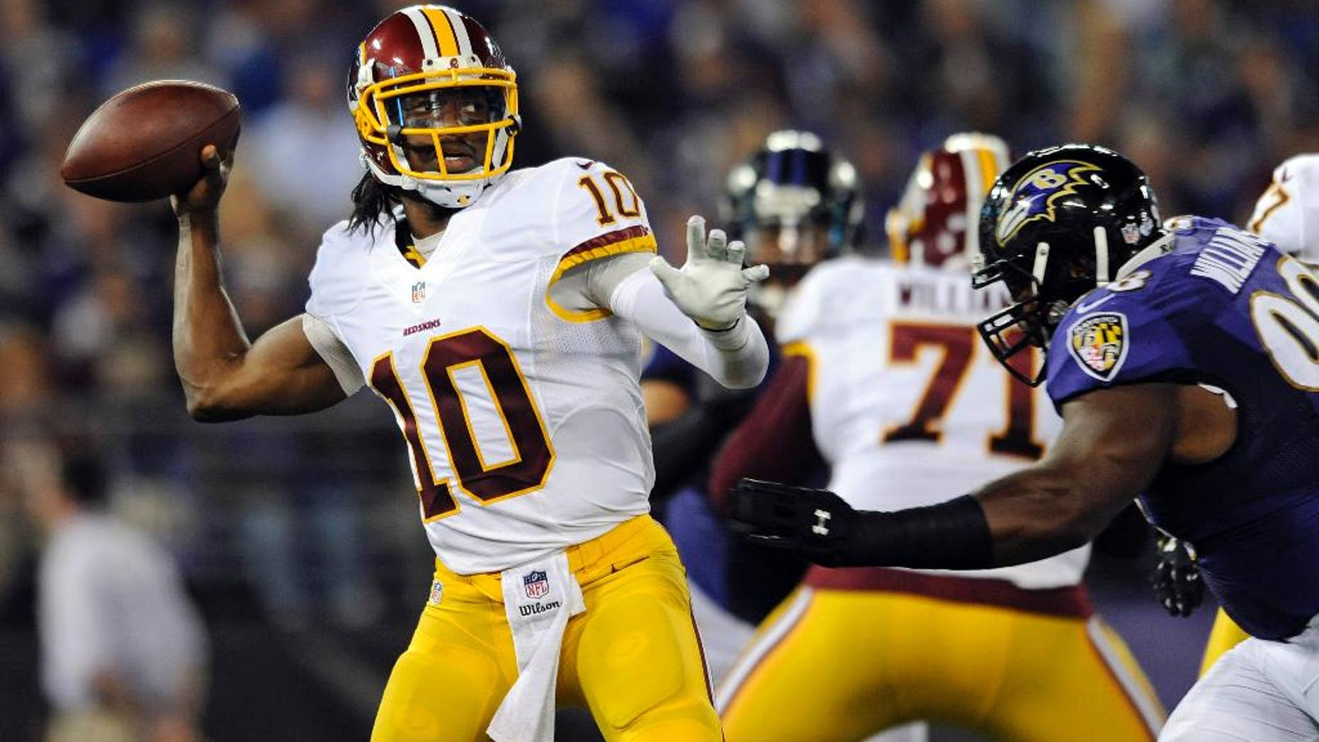 Washington Redskins quarterback Robert Griffin III, (10) throws to a receiver as he is pressured by Baltimore Ravens defensive tackle Brandon Williams in the first half of an NFL preseason football game, Saturday, Aug. 23, 2014, in Baltimore. (AP Photo/Gail Burton)