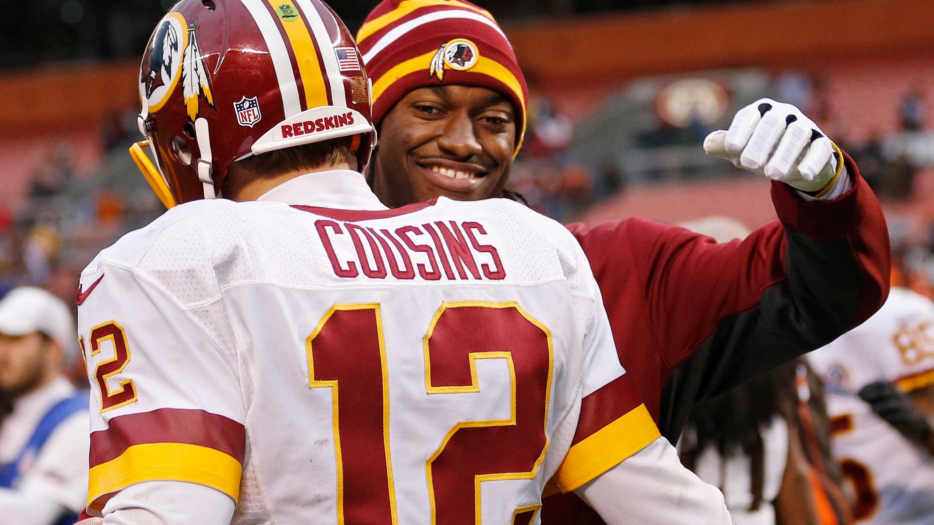 Injured Washington Redskins quarterback Robert Griffin III, right, hugs Kirk Cousins (12) after a 38-21 win over the Cleveland Browns in an NFL football game in Cleveland, Sunday, Dec. 16, 2012. Cousins passed for 329 yards and two touchdowns filling in for Griffin. (AP Photo/Rick Osentoski)