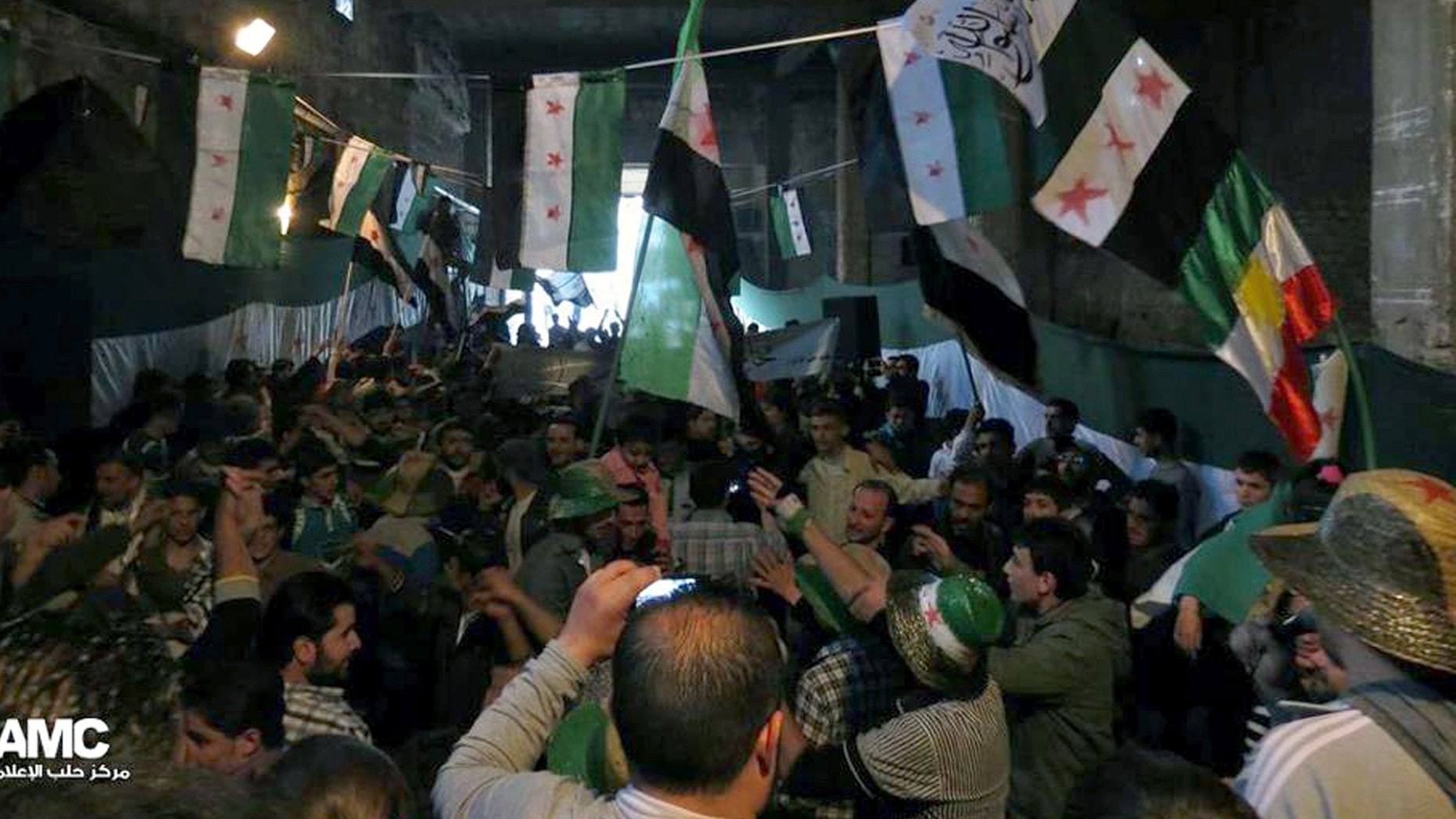 FILE: aPRIL 17, 2013: Anti-Syrian regime protesters holding Syrian revolution flags during a rally. The image provided by Aleppo Media Center AMC has been authenticated based on its contents and other reporting.