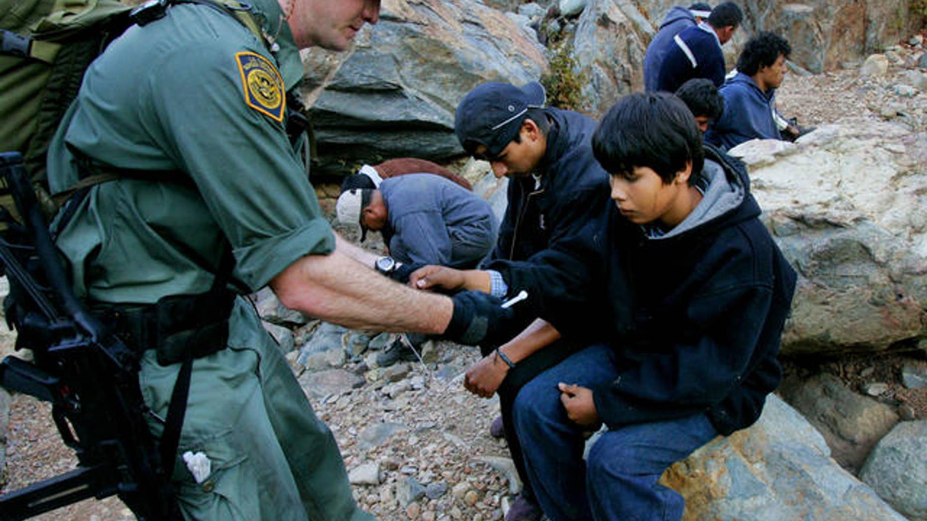 Border patrol agent Jeff Mielke secures plastic handcuffs on a group of undocumented immigrants caught in the Otay Mesa Mountain Range, just east of San Diego.