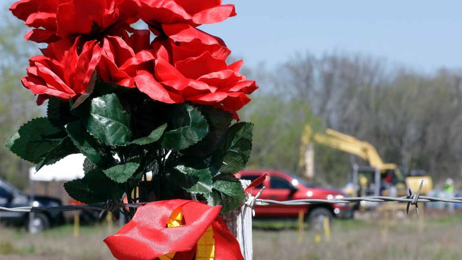 FILE - In this file photo made March 4, 2016, flowers hang on a fence surrounding an area where authorities search for human remains near Houston. A convicted kidnapper has been temporarily released from prison to help authorities who are digging for the body of a teenager who disappeared two decades ago. Denton police say the remains have been identified through dental records as those of Kelli Cox, who went missing from the North Texas town of Denton in July 1997. (AP Photo/David J. Phillip, file)