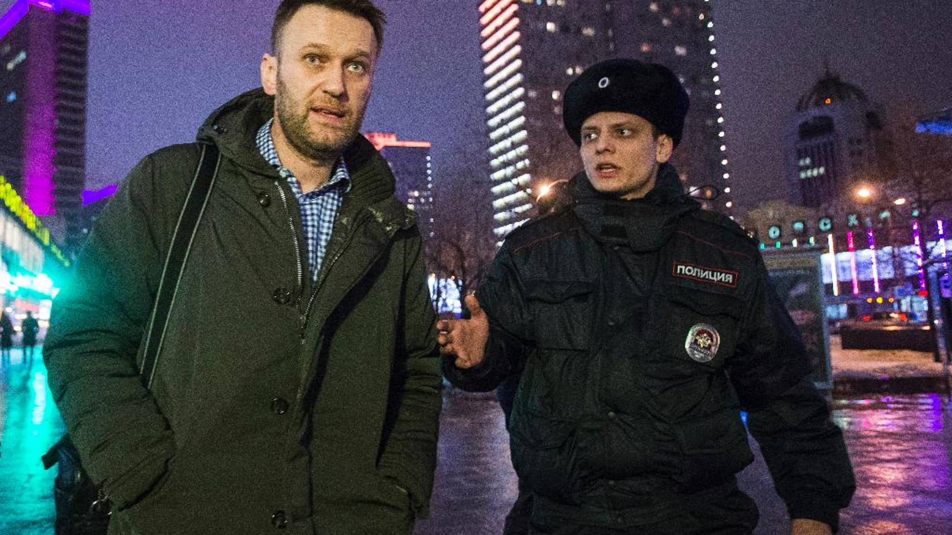 Russian opposition activist and anti-corruption crusader Alexei Navalny, left, is detained by police after defying his house arrest to speak on Radio Echo Moskvy in Moscow, Wednesday, Jan. 14, 2015. Leading Russian opposition figure Alexei Navalny says he has paid the state for the electronic bracelet that he cut off to protest his house arrest. Navalny was convicted in late December of fraud and given a suspended sentence. But the court said he must remain under house arrest until his appeals are exhausted. (AP Photo/Pavel Golovkin)
