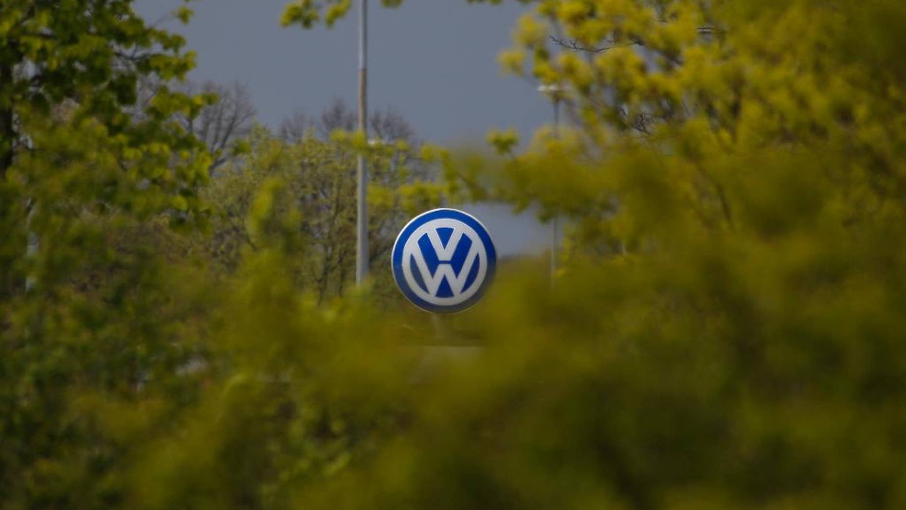 FILE - In this April 28, 2016 file picture Volkswagen logo at a factory entrance stands behind green bushes during the company's annual press conference in Wolfsburg, Germany. Volkswagen says Wednesday July 27, 2016 its global sales rose 5.1 percent in June compared with a year earlier, fueled by gains in China and Europe and bolstering its performance over the year's first half. Deliveries in the U.S. were down significantly. (AP Photo/Markus Schreiber,file)
